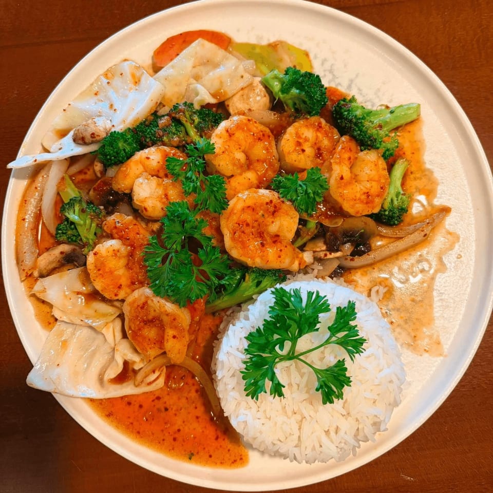 Spicy shrimp stir-fry with broccoli, cabbage, and mushrooms, served with white rice and parsley.